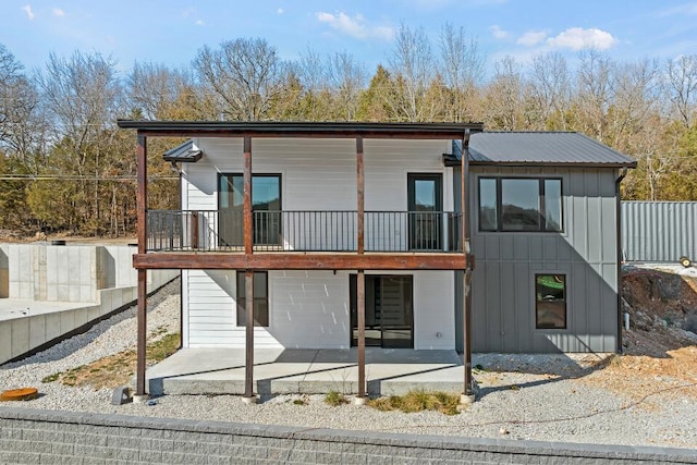 rear view of house featuring a patio area, fence, metal roof, and board and batten siding