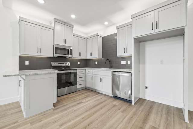 kitchen with white cabinetry, appliances with stainless steel finishes, tasteful backsplash, and light wood-type flooring