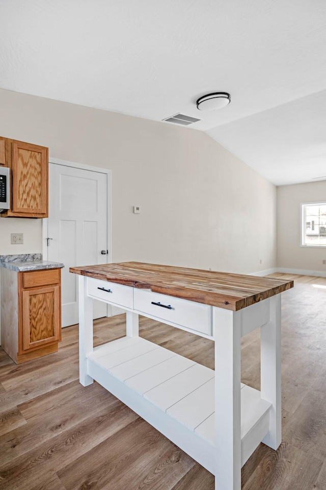 interior space featuring light wood-type flooring, vaulted ceiling, and butcher block counters