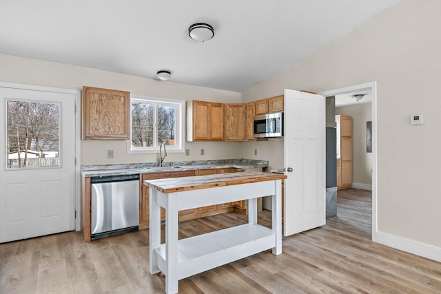 kitchen with light hardwood / wood-style floors, sink, stainless steel appliances, and vaulted ceiling