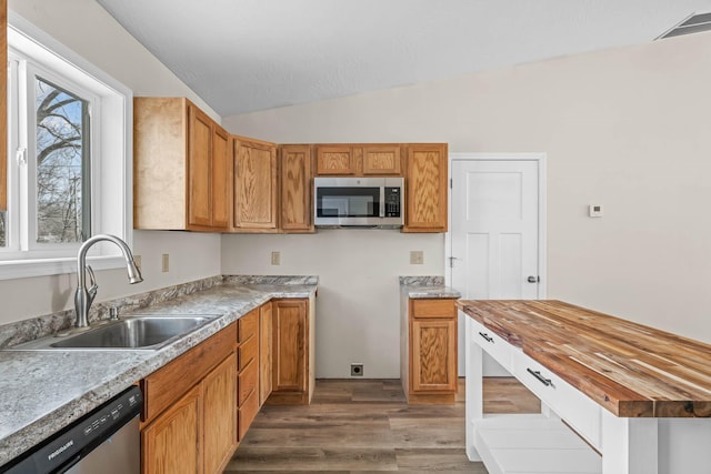 kitchen with vaulted ceiling, sink, appliances with stainless steel finishes, dark hardwood / wood-style flooring, and wood counters