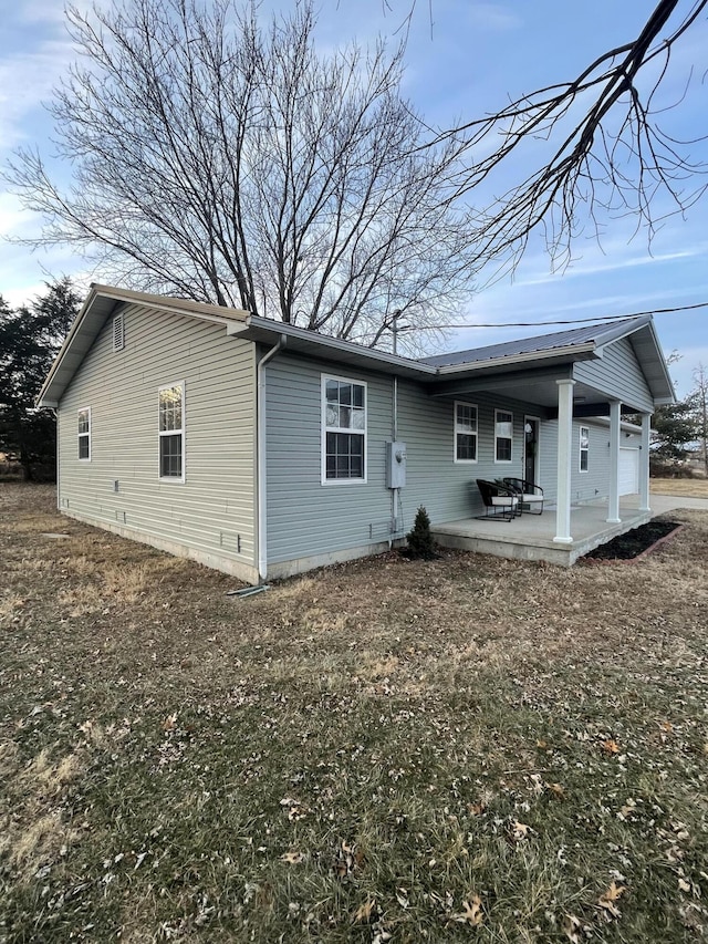 back of house with a garage, a yard, and a patio