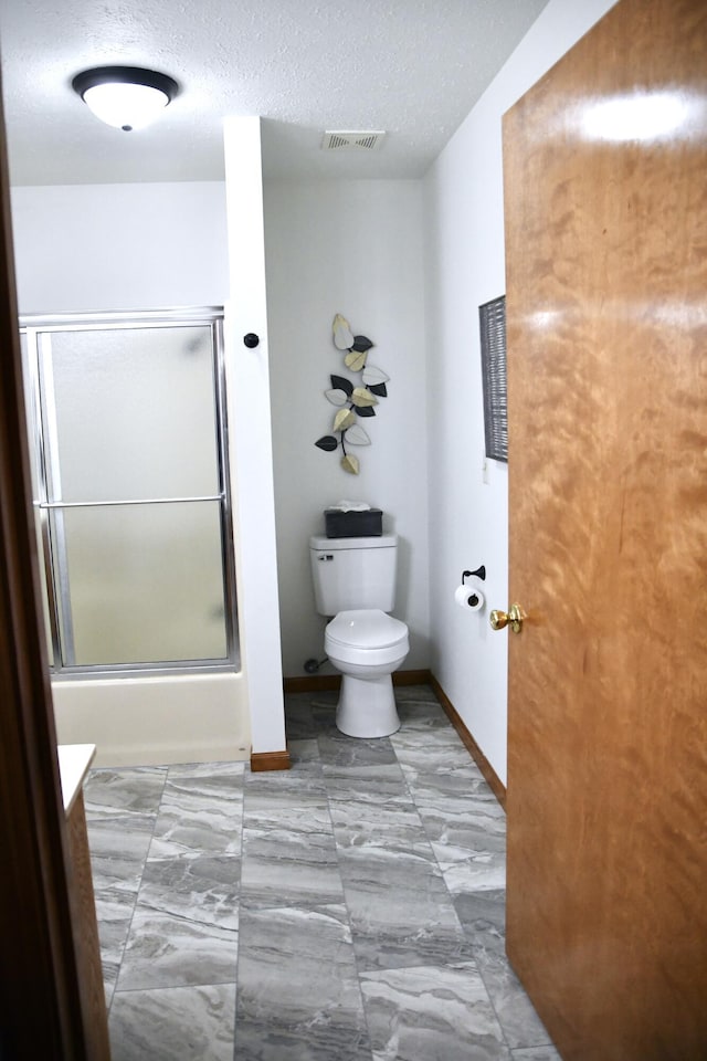 full bathroom featuring a textured ceiling, toilet, enclosed tub / shower combo, and vanity