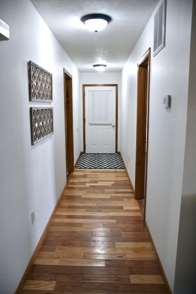 hall featuring hardwood / wood-style flooring and a textured ceiling