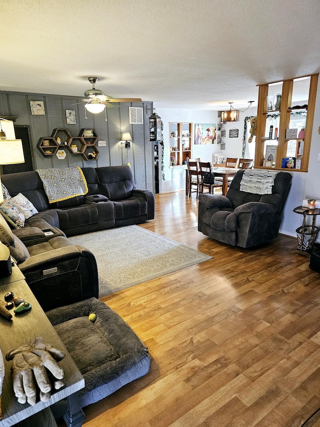 living room with wood-type flooring, ceiling fan, and a textured ceiling