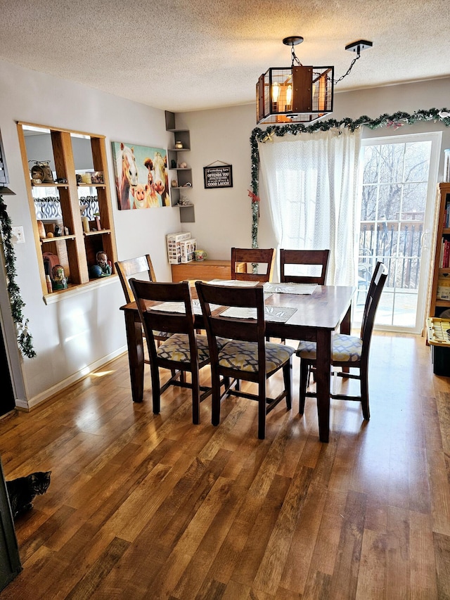 dining room with dark wood-type flooring, a textured ceiling, and a notable chandelier