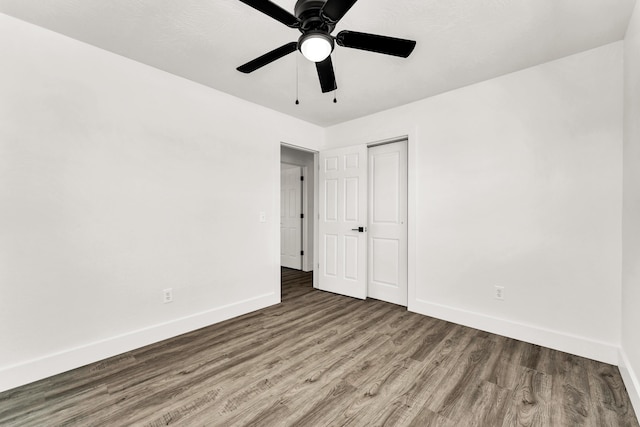 unfurnished bedroom with ceiling fan, a closet, and hardwood / wood-style floors