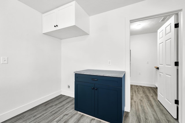 kitchen with blue cabinetry, a textured ceiling, and light wood-type flooring