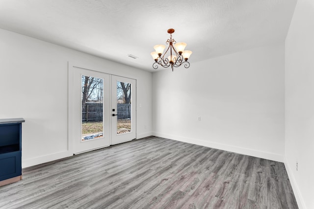 unfurnished room with french doors, a notable chandelier, and light hardwood / wood-style flooring