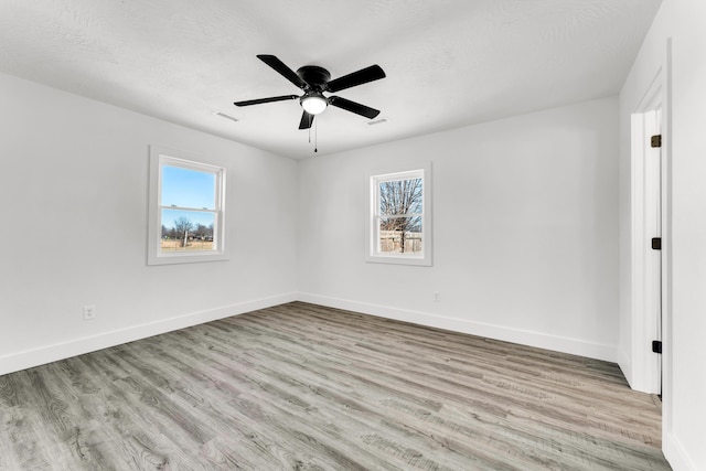 empty room featuring light hardwood / wood-style floors, a textured ceiling, ceiling fan, and a healthy amount of sunlight