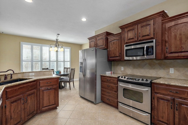 kitchen with appliances with stainless steel finishes, backsplash, pendant lighting, light stone counters, and sink