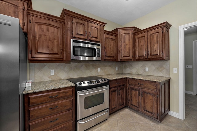 kitchen with light tile patterned floors, backsplash, light stone countertops, and stainless steel appliances