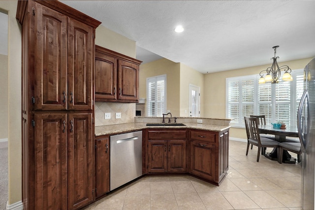 kitchen featuring pendant lighting, stainless steel appliances, sink, backsplash, and light stone counters