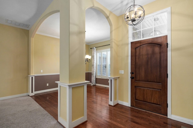 foyer featuring dark hardwood / wood-style flooring, crown molding, and a chandelier