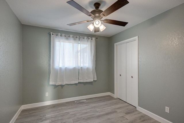 unfurnished bedroom featuring ceiling fan, light hardwood / wood-style floors, and a closet