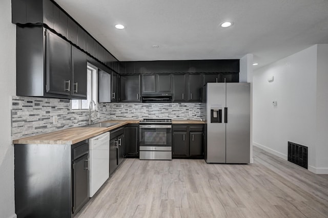 kitchen featuring wood counters, stainless steel appliances, decorative backsplash, light hardwood / wood-style flooring, and sink