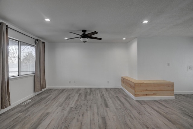 empty room with ceiling fan, a textured ceiling, and light hardwood / wood-style floors