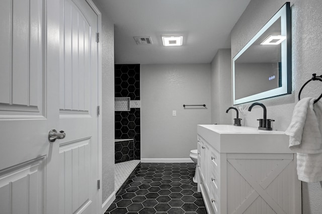 bathroom featuring vanity, toilet, tile patterned floors, and tiled shower