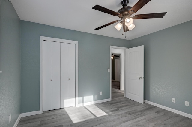 unfurnished bedroom with ceiling fan, a closet, and light wood-type flooring