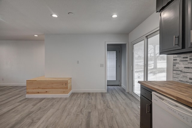 kitchen with a textured ceiling, dishwasher, light hardwood / wood-style flooring, and wooden counters