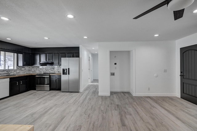 kitchen with ceiling fan, appliances with stainless steel finishes, decorative backsplash, light wood-type flooring, and sink