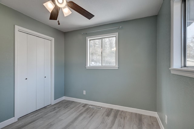 unfurnished bedroom with light wood-type flooring, ceiling fan, and a closet