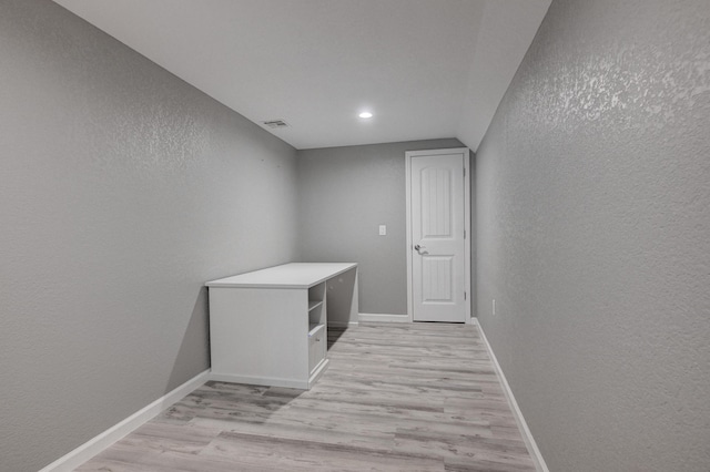 corridor with light wood-type flooring and lofted ceiling