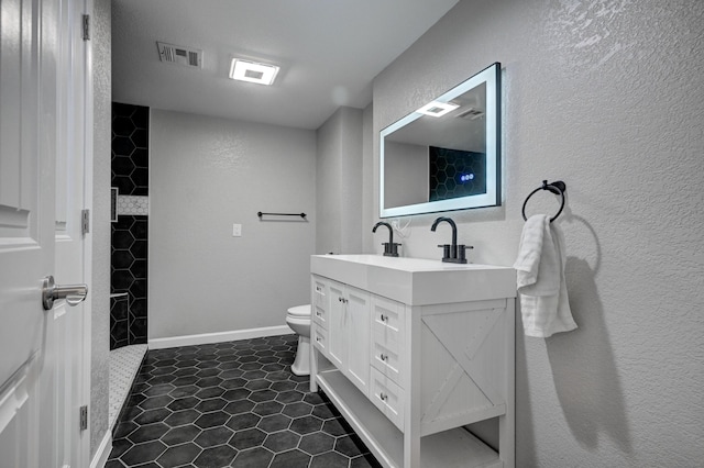 bathroom featuring tile patterned floors, toilet, vanity, and walk in shower