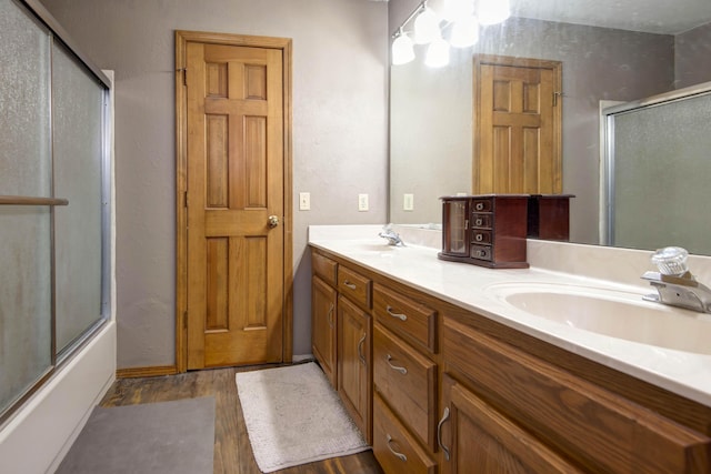 bathroom featuring hardwood / wood-style floors, enclosed tub / shower combo, and vanity