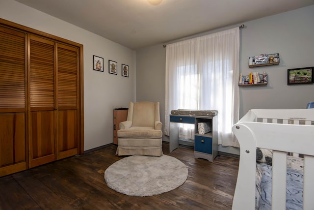 bedroom with dark wood-type flooring, a closet, and a crib