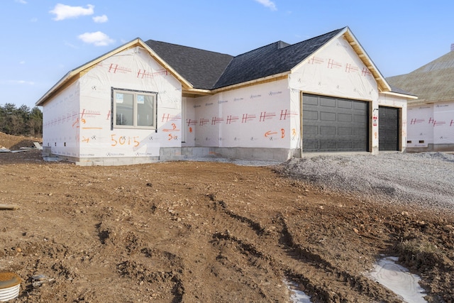 unfinished property featuring a shingled roof, driveway, and an attached garage