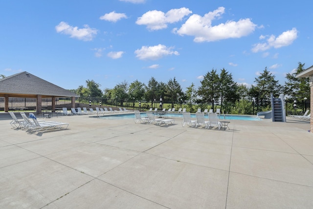 pool featuring a water slide, a patio area, fence, and a gazebo