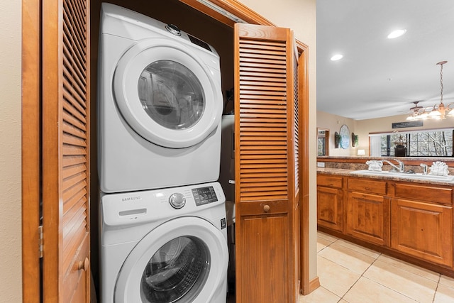 washroom featuring light tile patterned floors, sink, and stacked washer and clothes dryer