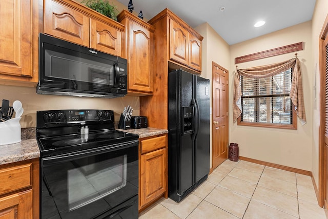 kitchen with light tile patterned floors, dark stone countertops, and black appliances