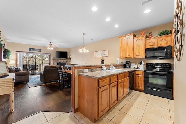 kitchen featuring black appliances, kitchen peninsula, sink, hanging light fixtures, and light tile patterned floors