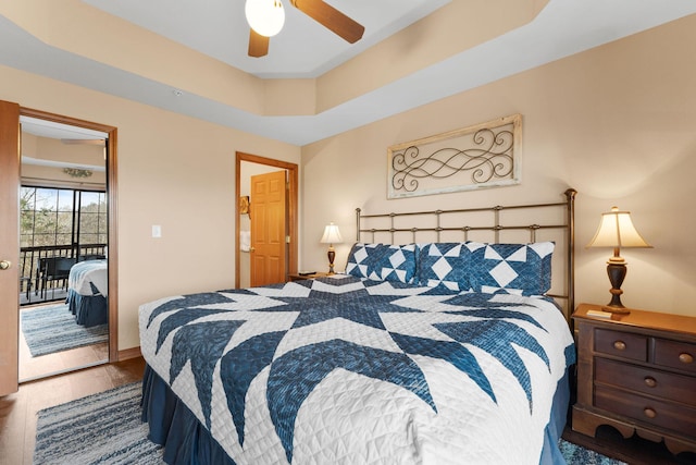 bedroom featuring ceiling fan, hardwood / wood-style flooring, a tray ceiling, and access to outside