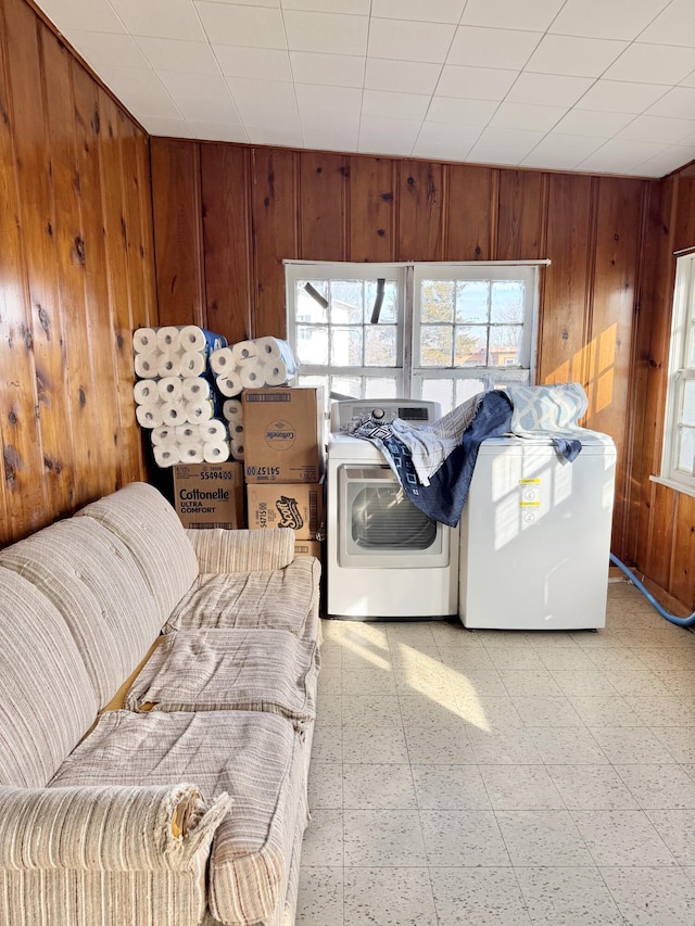 clothes washing area featuring washer and dryer and wooden walls