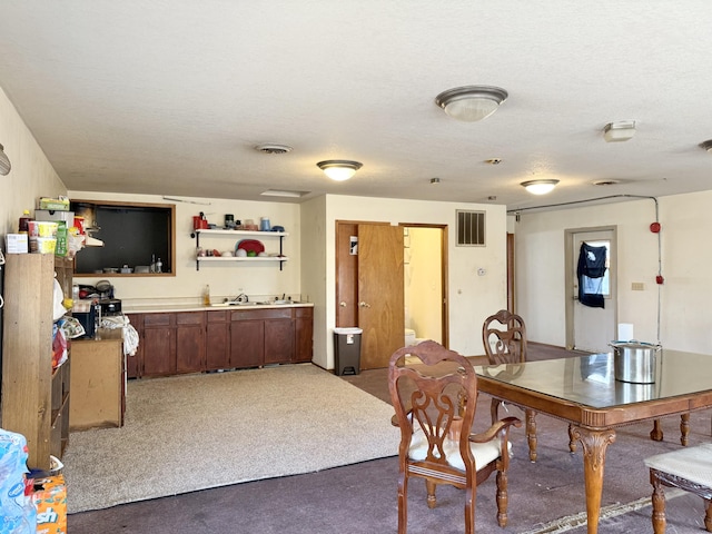 carpeted dining area featuring a textured ceiling