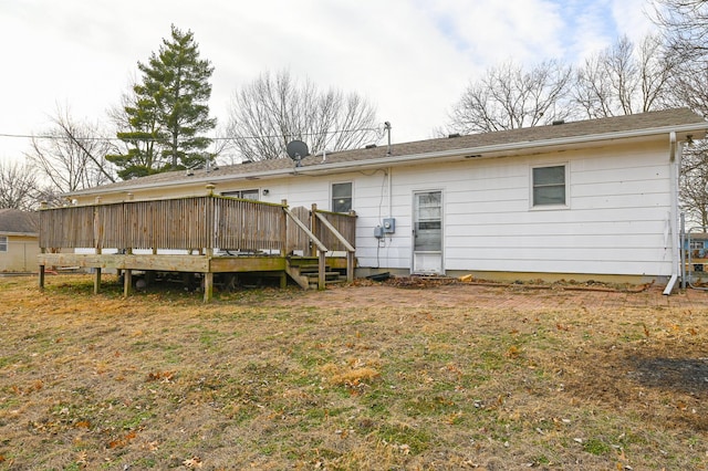 rear view of house featuring a wooden deck and a lawn