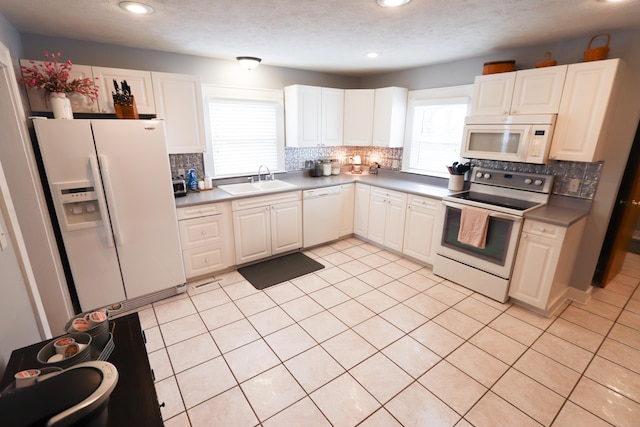 kitchen featuring white cabinetry, sink, white appliances, and light tile patterned floors