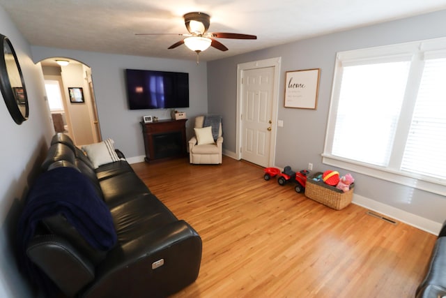 living room with ceiling fan, wood-type flooring, and a fireplace