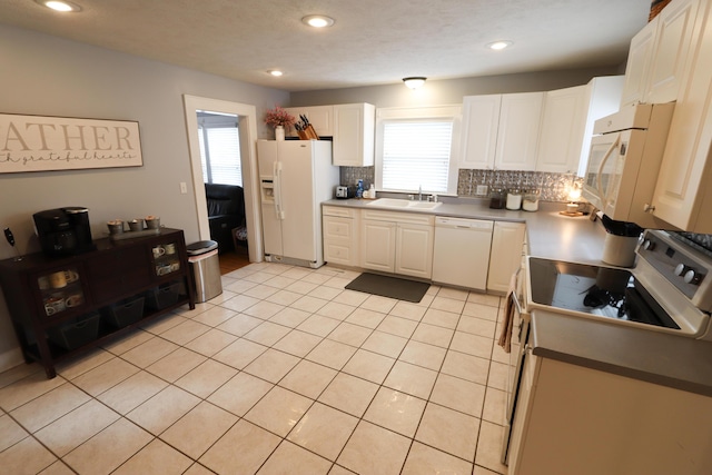 kitchen featuring light tile patterned floors, white cabinetry, decorative backsplash, white appliances, and sink