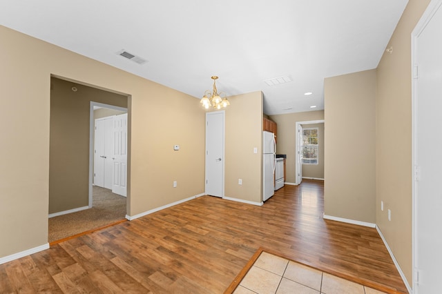 empty room featuring light wood-type flooring and a chandelier