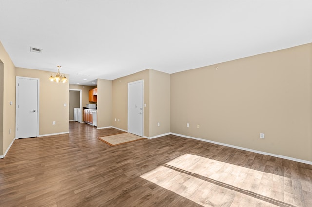 spare room featuring wood-type flooring and a notable chandelier