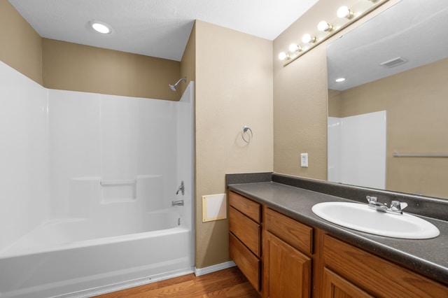 bathroom with tub / shower combination, hardwood / wood-style floors, and vanity