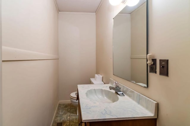 bathroom featuring toilet, ornamental molding, and vanity