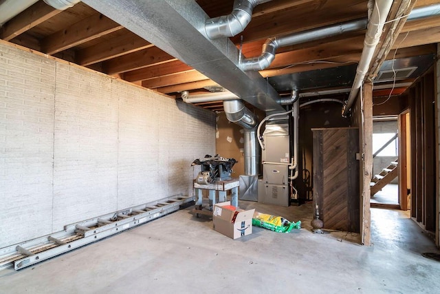 basement featuring heating unit and brick wall