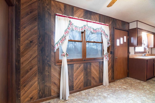 room details featuring a textured ceiling, ceiling fan, wooden walls, and sink