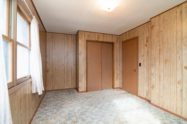 unfurnished bedroom with a closet, wood walls, and a textured ceiling