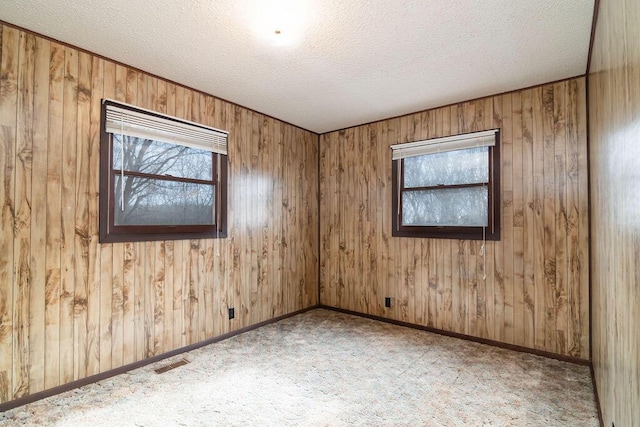 spare room featuring a textured ceiling and wooden walls